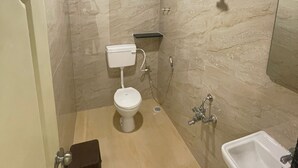 Un bagno compatto con WC, bidet e lavandino, caratterizzato da una parete in marmo e un soffitto scuro.