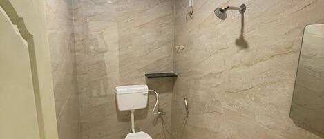 A compact bathroom with a toilet, bidet, and sink, featuring a marble wall and a dark ceiling.