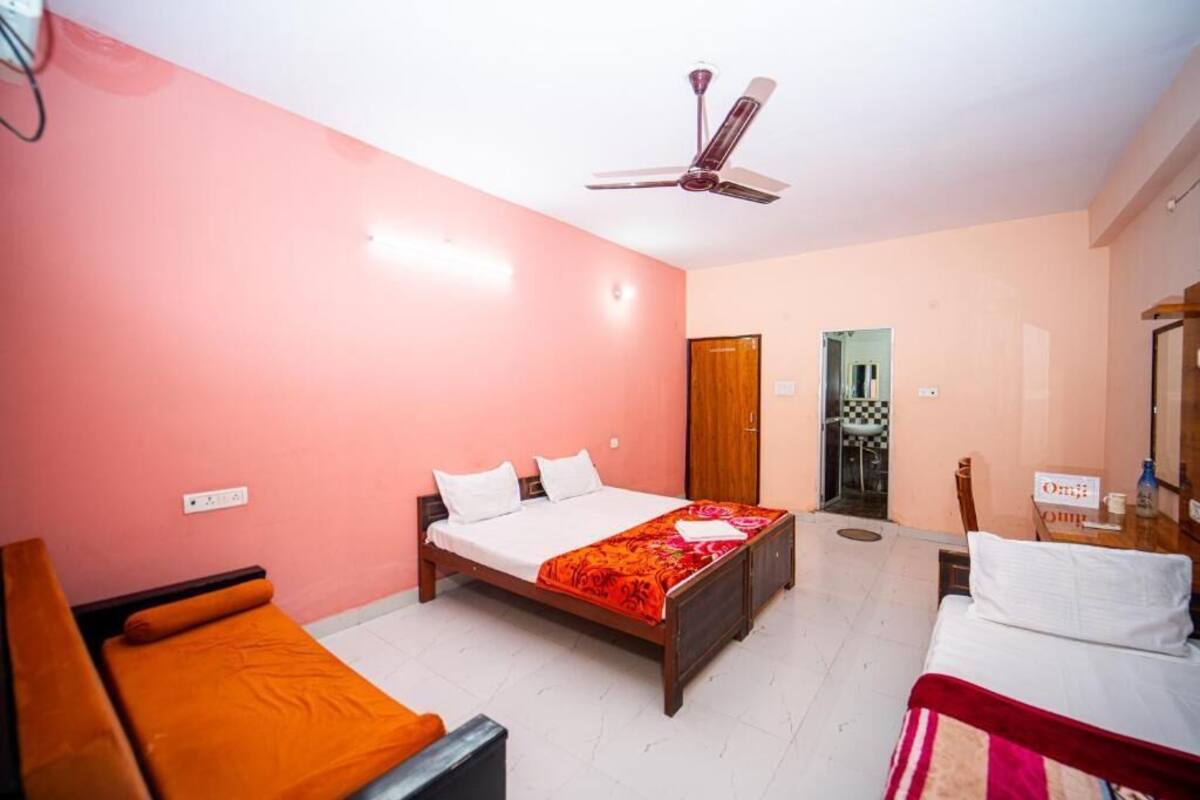 A hotel room with a bed, a sofa, a desk, and a ceiling fan.