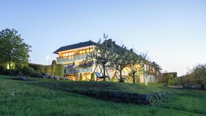 A multi-story building with a flat roof, surrounded by a grassy area and trees. - Landhotel Talblick  (Neuweiler)
