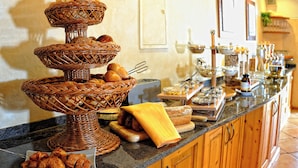 A buffet setup with wicker baskets, bread, and various food items on a granite countertop. - Landhotel Talblick  (Neuweiler)