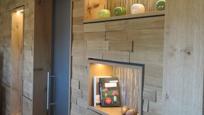 A modern kitchen with wooden wall paneling, a built-in shelf with decorative apples, and a book titled 'Mord Schwarzwald'. - Landhotel Talblick  (Neuweiler)