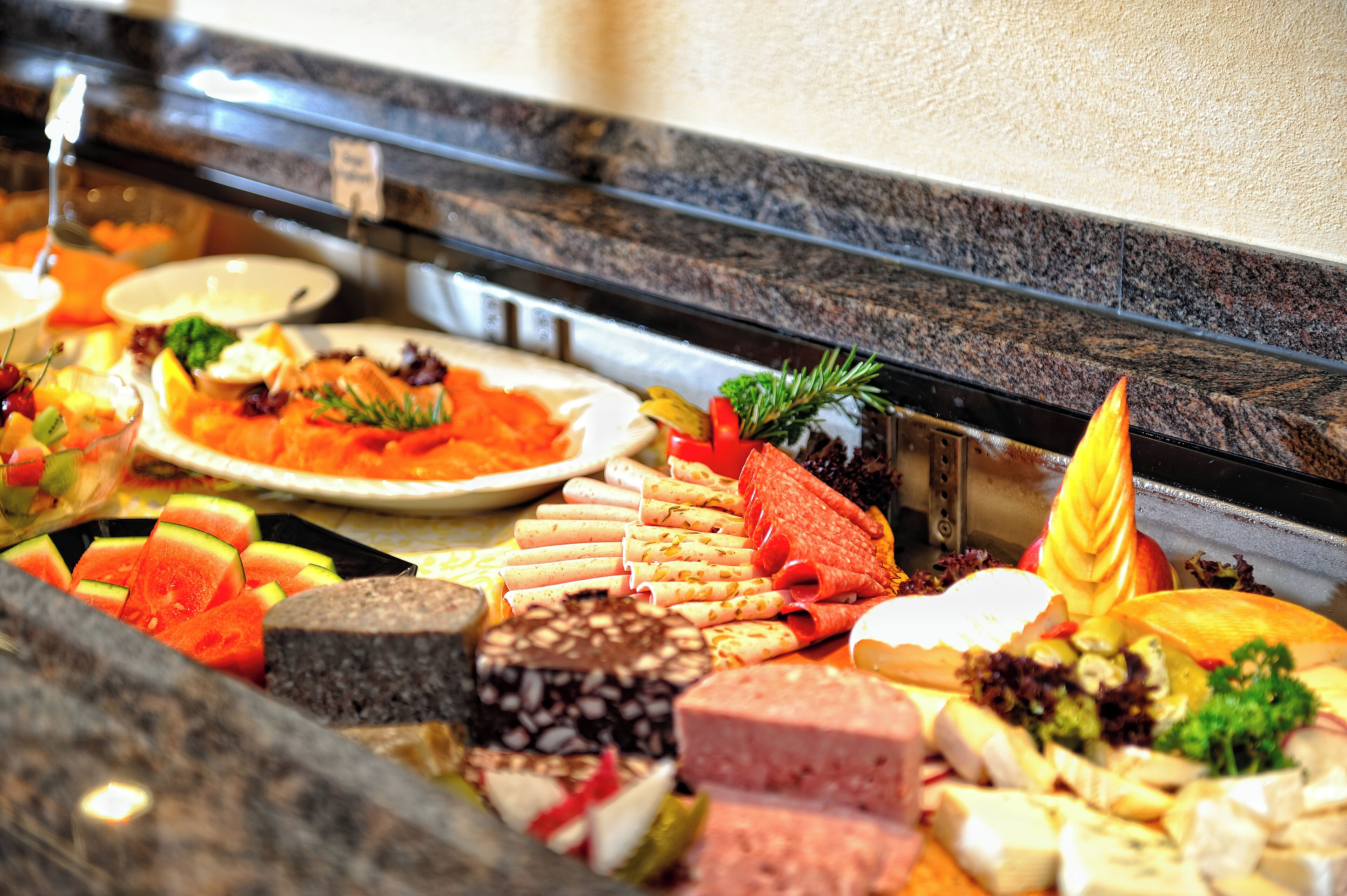 A buffet with various food items including meats, cheeses, and fruits.