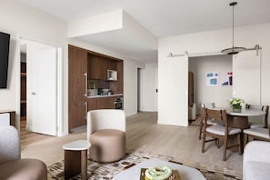 A modern living room with a sofa, ottoman, and dining area with chairs and a table. - Cozy 1BR Domus Brickell (Miami)