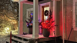 A house with a covered porch, steps leading up to the entrance, and Christmas lights.