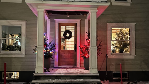 A house with a porch, a wreath on the door, and Christmas lights.