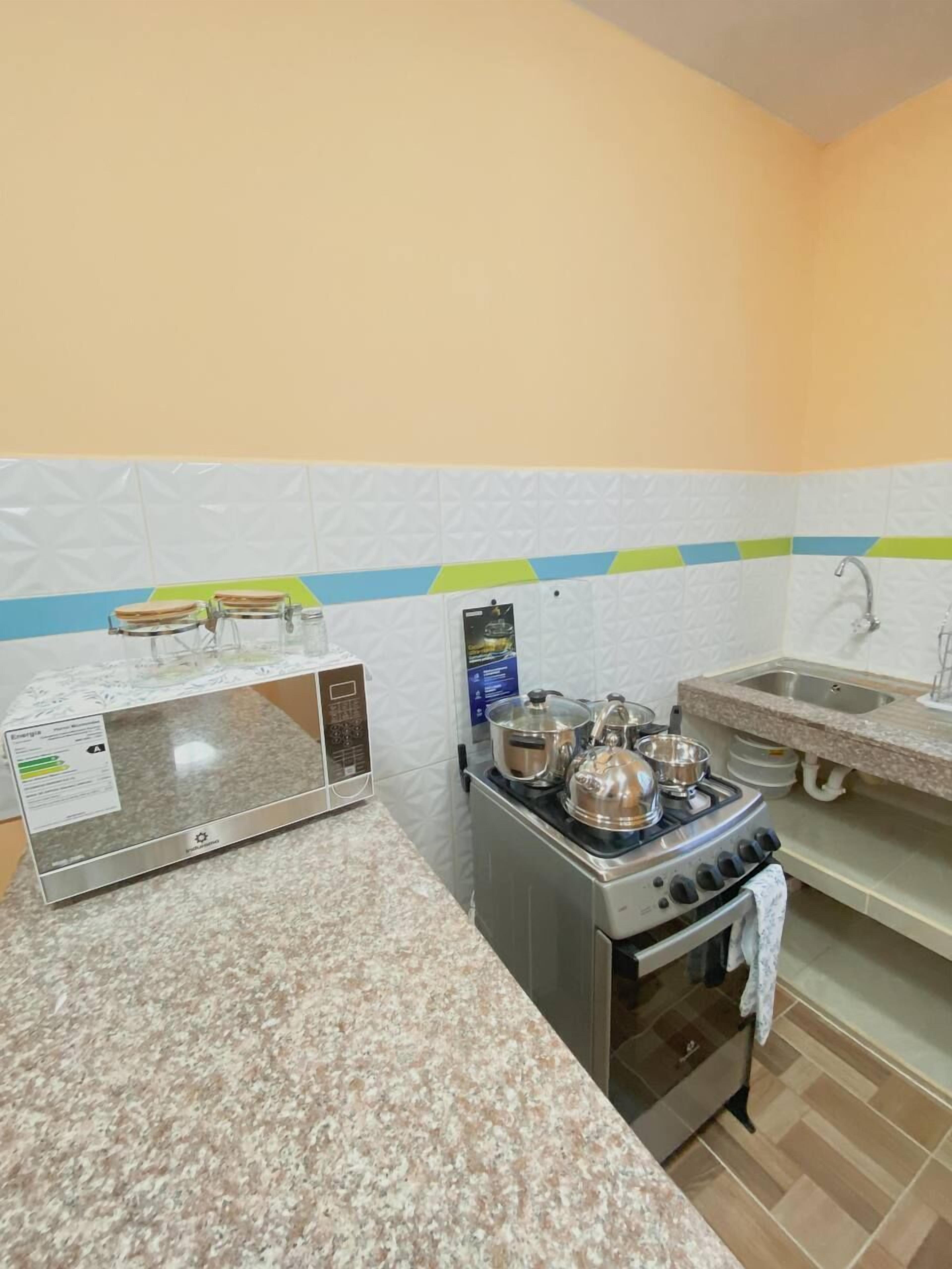 A compact kitchen with a microwave, stove, and sink.