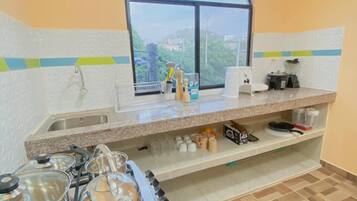 A kitchen with a gas stove, a sink, a window with a view, and a countertop with various items.