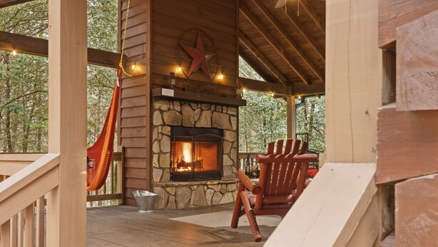 Un espace extérieur abrité, doté d’une cheminée en pierre, d’une terrasse en bois et d’une décoration en forme d’étoile rouge.