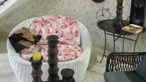 Una sala de estar con una silla de mimbre, una mesita con una lámpara y una escalera.