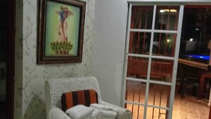Una sala de estar con un sofá de mimbre, un cuadro en la pared y un ventanal corredizo que da a un espacio al aire libre.