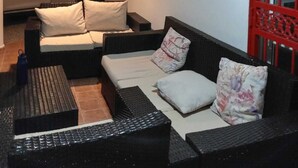 Habitación con sofá, una mesita, lámpara colgante y ventana con vista a un coche.
