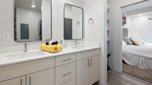 A modern bathroom with a double sink, two mirrors, and a towel rack.