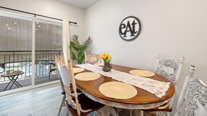 A dining area with a round table, chairs, a vase with flowers, and a wall sign.