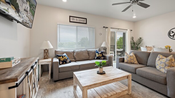 A living room with a sofa, coffee table, and a TV mounted on the wall.