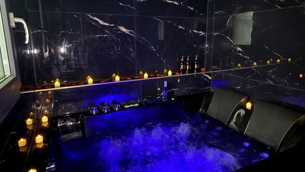 Spa-område med marmorvæg, jacuzzi og stearinlys.