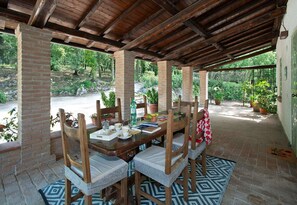 Eine Terrasse im Freien mit Holztisch, Stühlen und Kübelpflanzen.