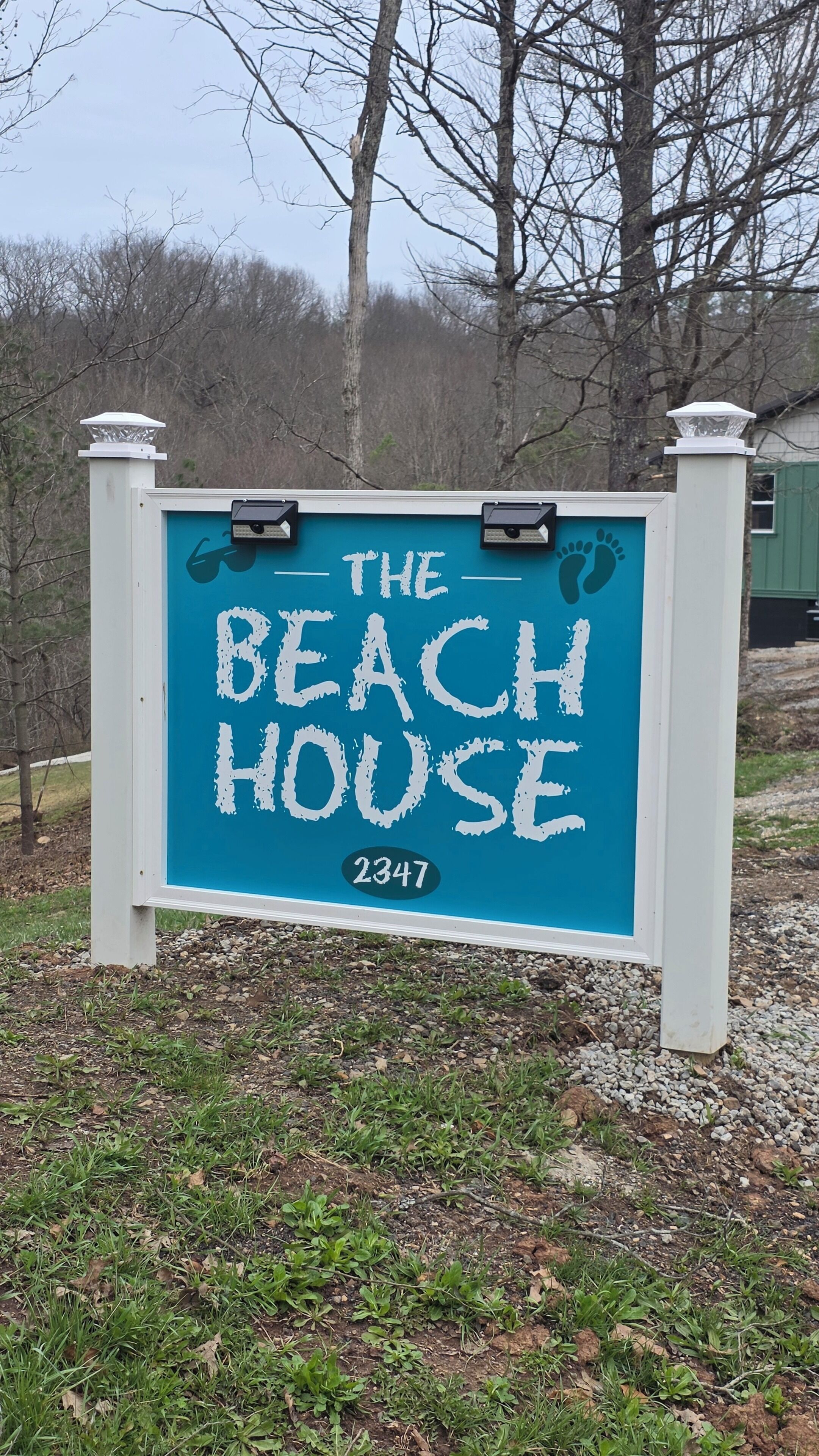 A sign with 'THE BEACH HOUSE' and the number '2347' on a blue background.