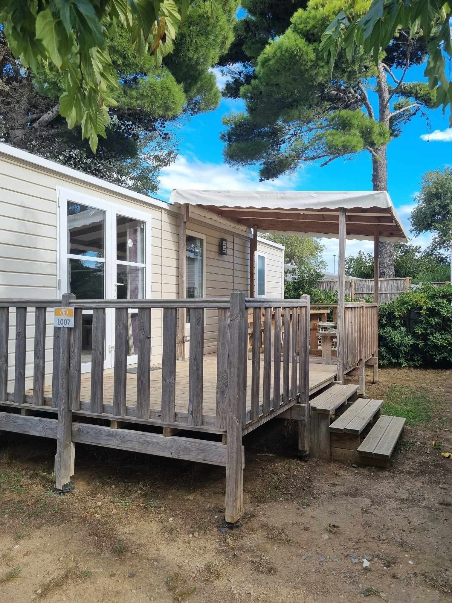 A wooden deck leading to a small cabin with a covered patio area.