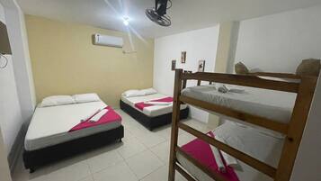 Una habitación con literas, ventilador de techo, aire acondicionado y piso de baldosas.