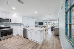 A modern kitchen with white cabinetry, stainless steel appliances, and a wooden floor. - Renovated Spacious Condo! Two Resort Pools! (Miramar Beach)