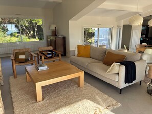 A modern living room with a sofa, armchairs, a coffee table, and a dining area with a table and chairs. - Large vacation home 15p, swimming pool and sea view of the Sanguinaires Islands (Coti-Chiavari)
