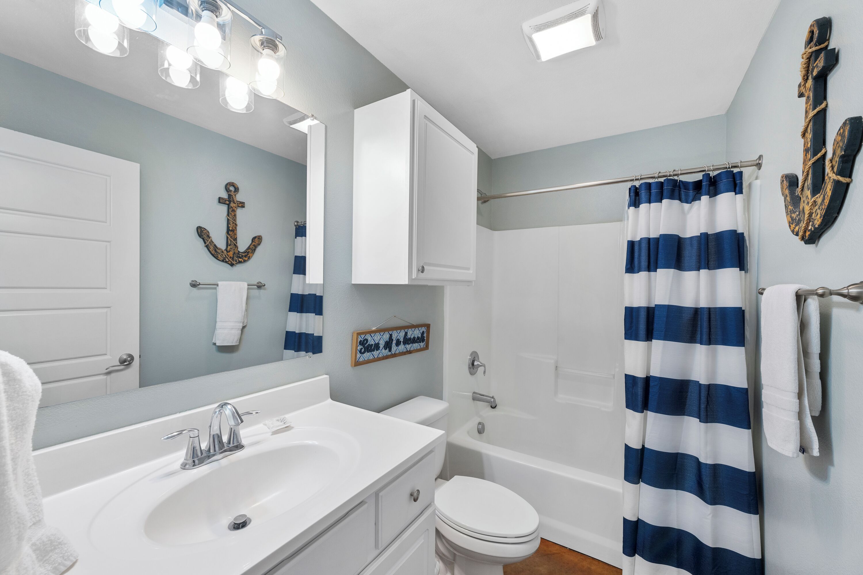 Een badkamer met een wit wastafelmeubel, een wit toilet, een bad en een douchegordijn.