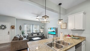 A modern kitchen with granite countertops, stainless steel appliances, and pendant lighting. - Dog-Friendly Townhome | Heated Pool & Short Walk to Beach (Corpus Christi)