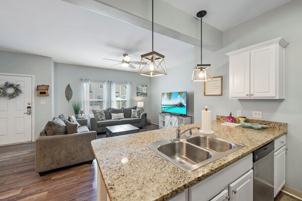 A modern kitchen with granite countertops, stainless steel appliances, and pendant lighting. - Dog-Friendly Townhome | Heated Pool & Short Walk to Beach (Corpus Christi)