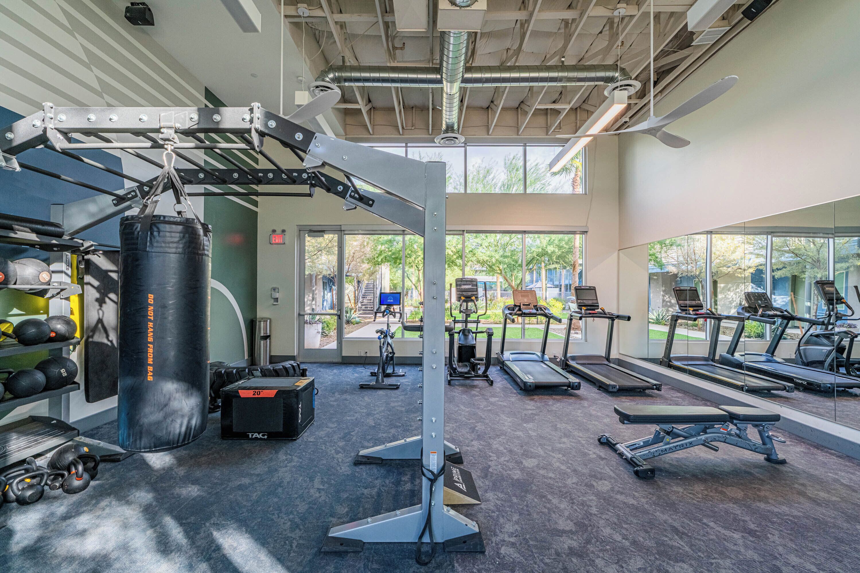 Une salle de sport équipée de tapis de course, d’un sac de frappe et de matériel de musculation.