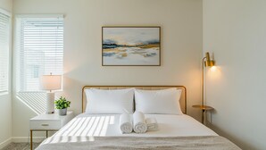 A neatly arranged hotel room with a bed, bedside table, lamp, and a painting on the wall. - Sleek Stay 4mins to State Farm Stadium (Glendale)