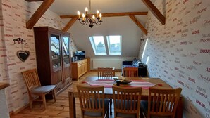 Een knus ingerichte kamer met een eettafel, stoelen, een kast en een televisie.