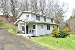 A two-story house with a porch, a driveway, and a well-maintained lawn. - Bradford County Creekside Country Retreat (Millerton)