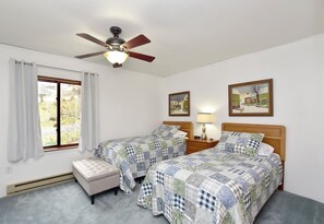 A bedroom with two beds, a ceiling fan, a window with curtains, and a small table with a lamp. - Bradford County Creekside Country Retreat (Millerton)