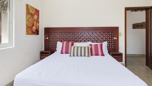 A neatly made bed with a wooden headboard, a bedside table, and a wall-mounted artwork. - Two Bedroom Penthouse Palapa Ocean View (Puerto Escondido)