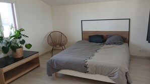 A bedroom with a bed, a chair, a potted plant, and a window. - House with sea view, a few steps from the magnificent Gouérou beach. (Lampaul-Plouarzel)