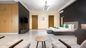 A hotel room with a bed, seating area, wardrobe, and a television.