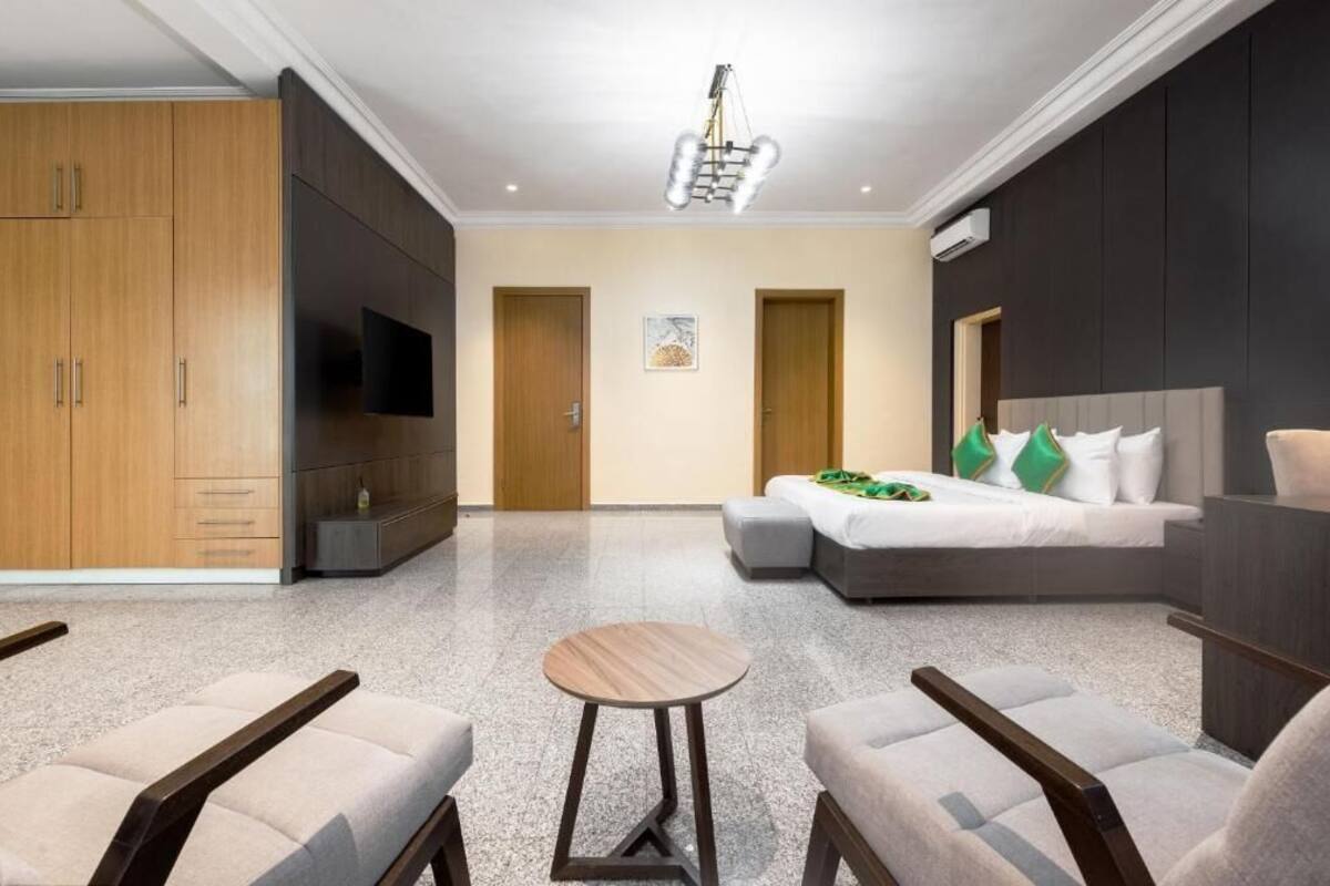 Una habitación de hotel con cama, zona de estar, armario y televisión.