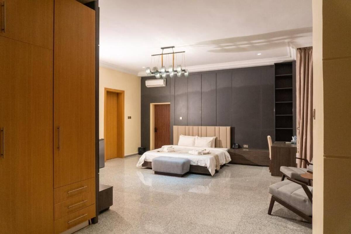 Un dormitorio moderno con una cama grande, un armario de madera, un escritorio y una silla.