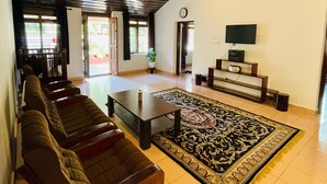 A spacious living area with a sofa, a coffee table, a TV, and a patterned rug. - Wonderful 4-bedroom cottage in Kalpetta for a relaxing getaway (Kalpetta)