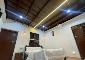 Une chambre avec un plafond en bois, un lit, une armoire et une fenêtre.