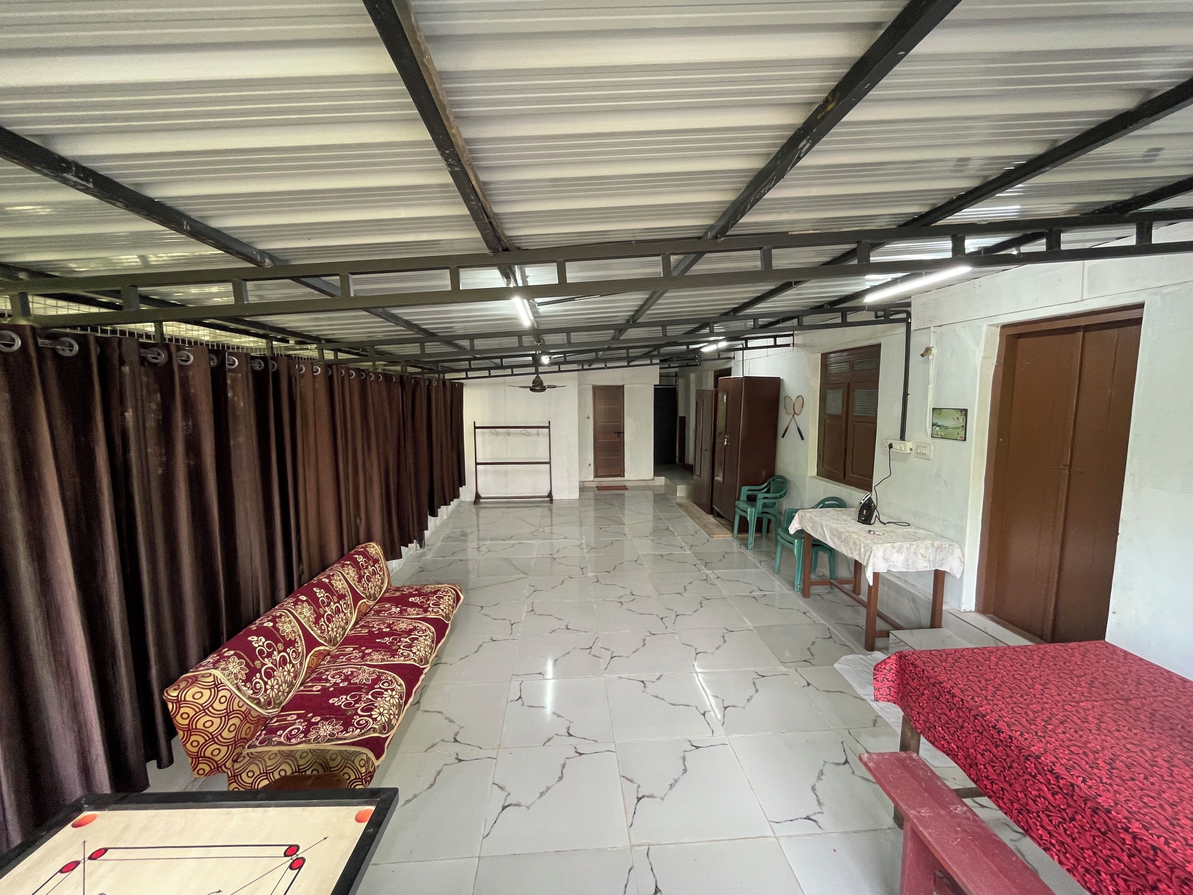 A room with a long bench, a table with a red tablecloth, and a ceiling fan.