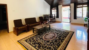 A spacious living area with a large, ornate rug, a ceiling fan, and a seating arrangement. - Wonderful 4-bedroom cottage in Kalpetta for a relaxing getaway (Kalpetta)