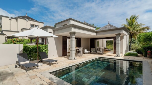 Una casa moderna con piscina, mobiliario exterior y un patio cubierto.