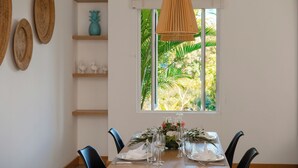 Un comedor con una mesa dispuesta para seis, una lámpara colgante y una ventana con vistas a zonas verdes.