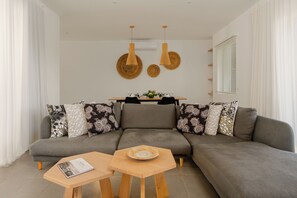 Uma sala de estar moderna com um sofá modular cinza, uma mesa de centro de madeira e uma pequena mesa lateral.