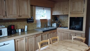 Uma cozinha com armários de madeira, pia, fogão e uma mesa de jantar com cadeiras.