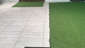A room with a tiled floor, a green artificial turf area, a wooden door with glass panels, and a chalkboard on the wall. - Pousada simples  (Pinhais)