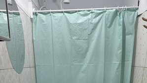 A bathroom with a toilet, sink, and shower curtain. - Pousada simples  (Pinhais)