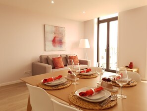 A modern dining area with a table set for four, a sofa, and a large window. -  São Gonçalinho Residence (Aveiro)
